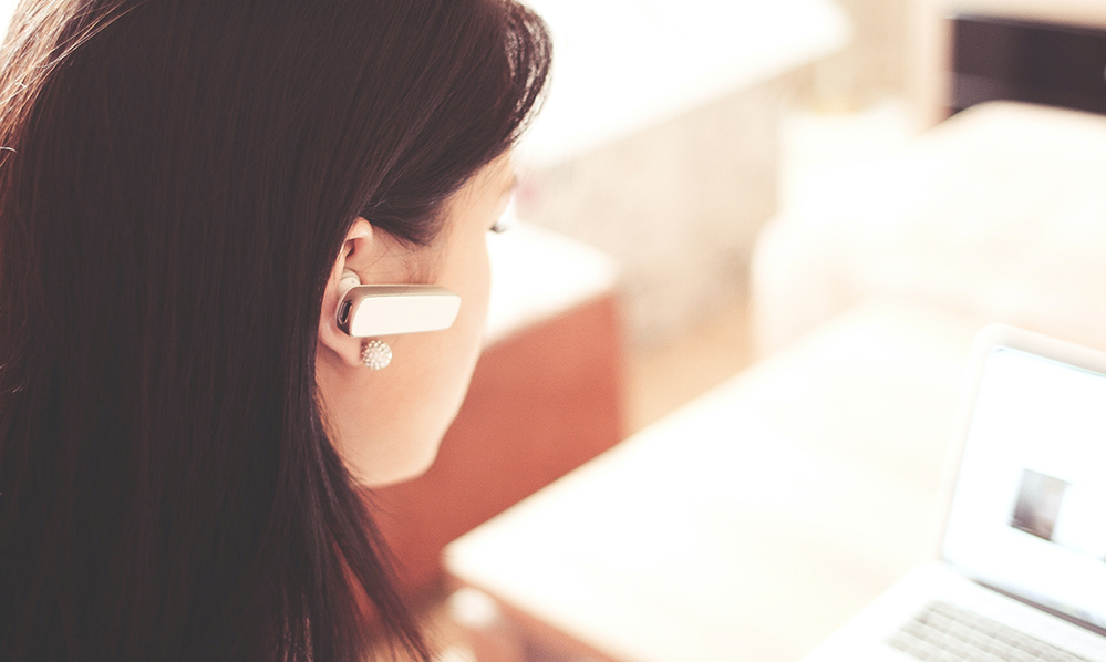 woman-wearing-earpiece-using-white-laptop-computer-210647